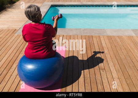 Senior woman exercising with dumbbells in the backyard of home Stock Photo