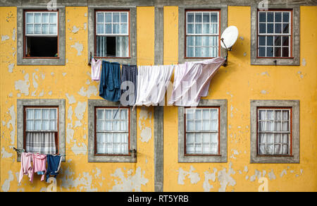 Beautiful and traditional facade of old building with clothes hanging from clothesline in windows. Stock Photo