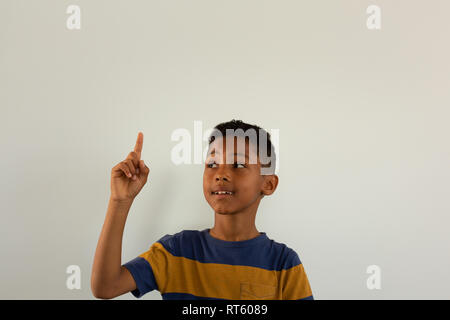 Thoughtful boy pointing his finger up while looking at his finger Stock Photo