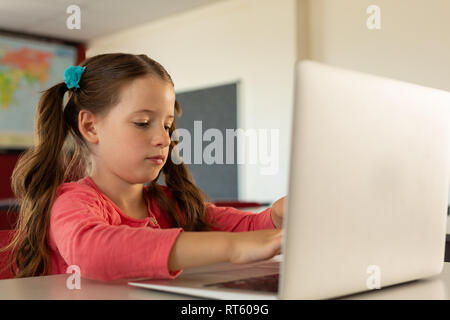 Girl using laptop in a classroom Stock Photo