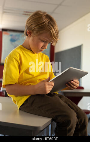 Boy sitting over desk and using digital tablet in a classroom Stock Photo