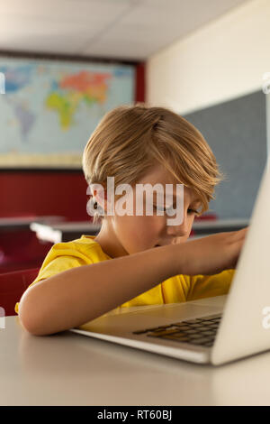 Boy using laptop at desk in a classroom Stock Photo