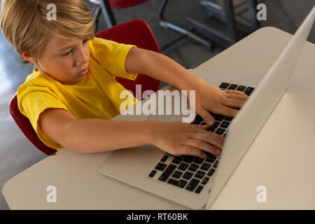 Boy using laptop at desk in a classroom Stock Photo