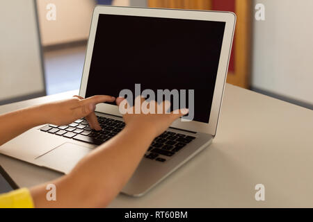 Boy using laptop at desk in a classroom Stock Photo