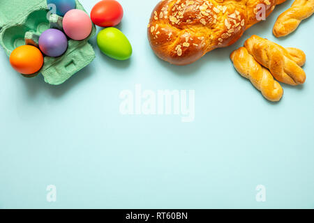 Easter eggs and tsoureki braid, greek easter sweet bread, on blue pastel color background, top view, copy space Stock Photo