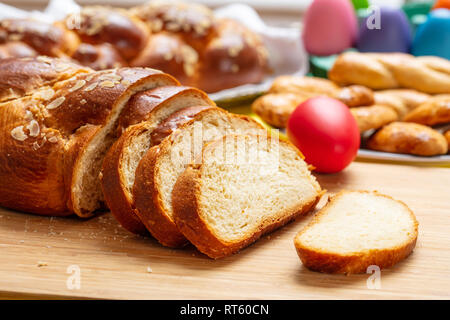 Easter eggs and tsoureki braid, greek easter sweet bread sliced on wood, banner, closeup view Stock Photo