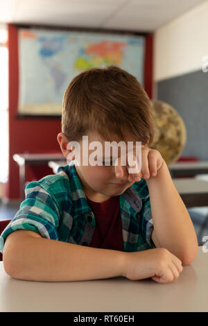 Boy with hand on head sleeping in a classroom Stock Photo