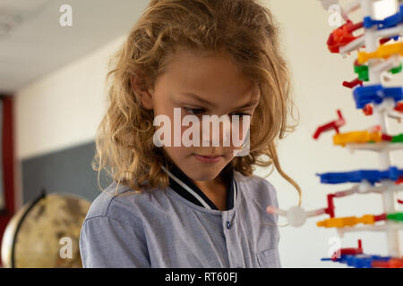 Schoolgirl learning on science model in classroom Stock Photo