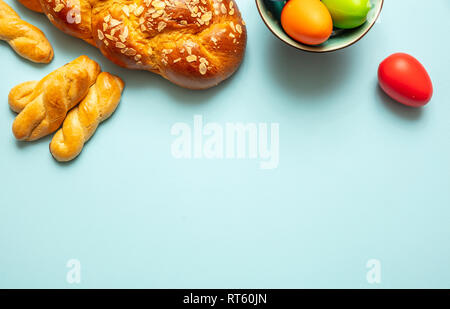 Easter eggs and tsoureki braid, greek easter sweet bread, on blue pastel color background, top view, copy space Stock Photo
