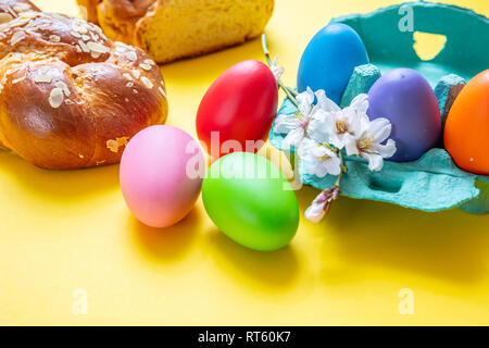 Easter eggs and tsoureki braid, greek easter sweet bread, on yellow color background Stock Photo