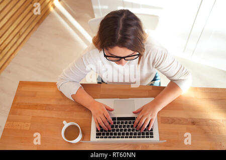 Top view of womans hands typing on laptop keypad wearing glasses and coffee on the table. Mock up minimal flat lay hero header Stock Photo