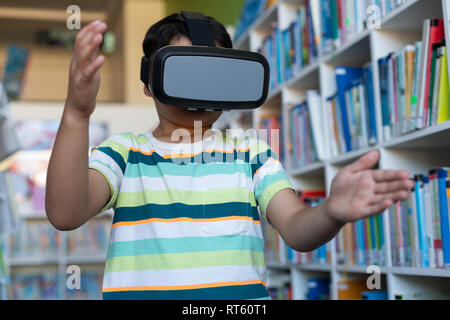 Schoolboy using virtual reality headset in library Stock Photo