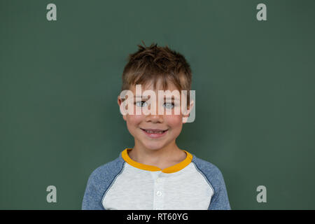 Schoolboy standing against greenboard in a classroom Stock Photo