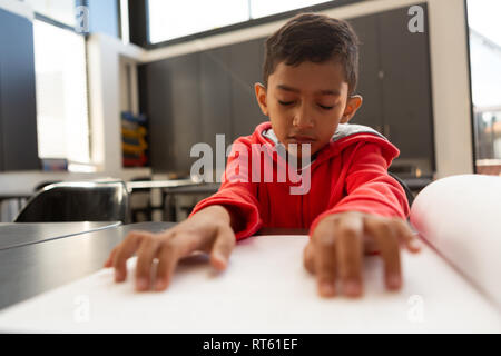 Blind schoolboy reading a braille book at desk in a classroom Stock Photo