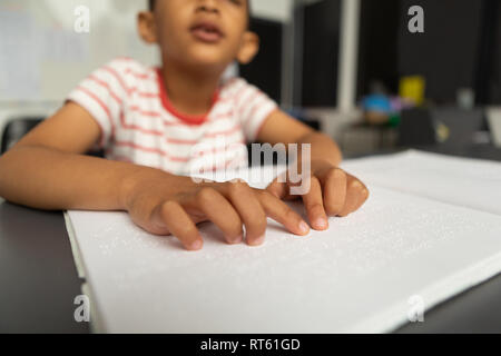 Blind schoolboy hands reading a braille book in classroom Stock Photo