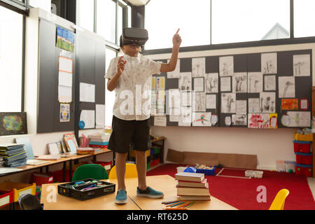 Schoolboy using virtual reality headset on a desk in classroom Stock Photo