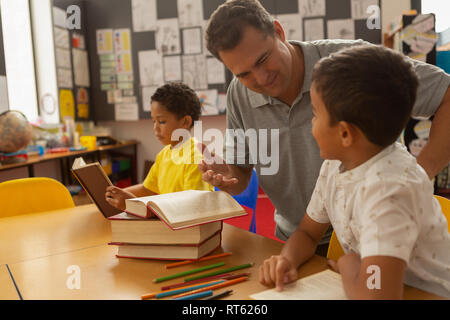 Male teacher teaching a schoolboy in a classroom Stock Photo