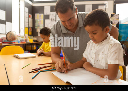 Male teacher teaching a schoolboy in a classroom Stock Photo