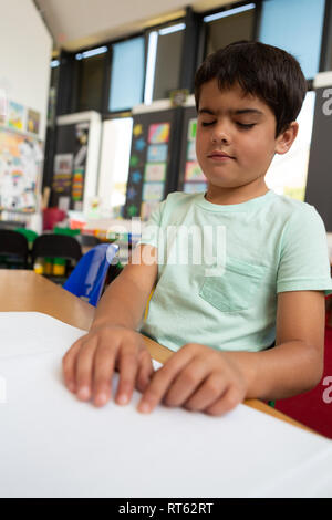 Blind schoolboy reading a braille book in the classroom Stock Photo