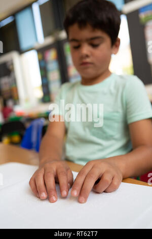 Blind schoolboy reading a braille book in the classroom Stock Photo