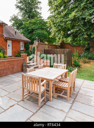 English garden and patio with wooden furniture outside a Victorian house in Buckinghamshire, UK