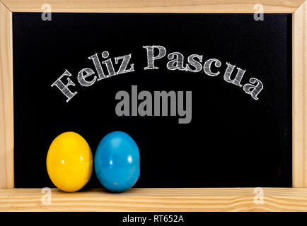 Easter frame with painted eggs and chalkboard. Happy Easter in white chalk. Happy Easter in spanish : feliz Pascua Stock Photo