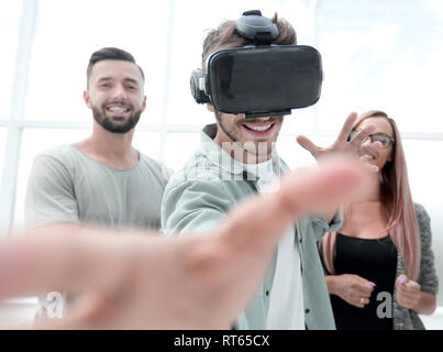 Young handsome man wearing virtual reality goggles touching controls to shoot in game Stock Photo