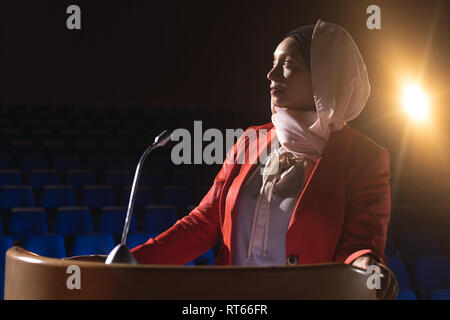 Businesswoman looking and thinking while standing on stage in auditorium Stock Photo