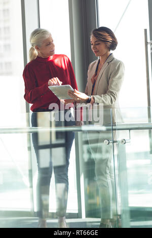Businesswomen discussing over digital tablet in office building Stock Photo