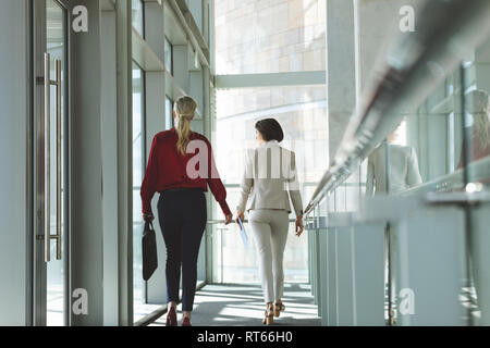 Businesswomen walking together in office Stock Photo