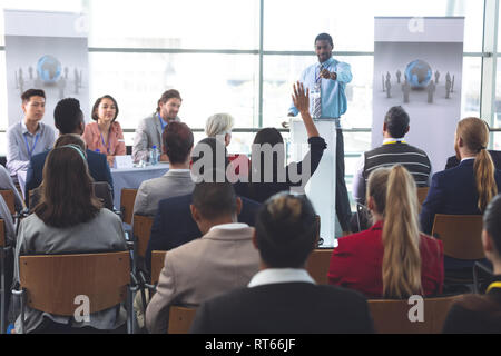 Businesswoman raising hand during business seminar Stock Photo