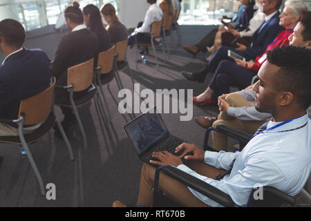 Disabled young businessman using laptop during seminar Stock Photo
