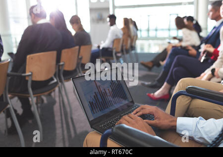 Disabled young businessman using laptop during seminar Stock Photo