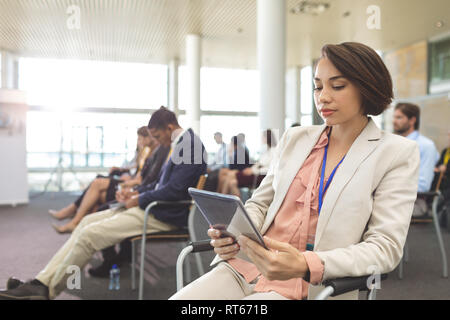 Happy young businesswoman using digital tablet during seminar Stock Photo