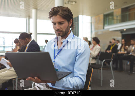 Young businessman using laptop during seminar Stock Photo