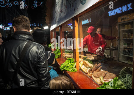 BELGRADE, SERBIA - DECEMBER 14, 2014: Crowd packing in front of a Rostilj stand with beef pattys (pljeskavica), meat fingers (cevapi) and sausages rea Stock Photo