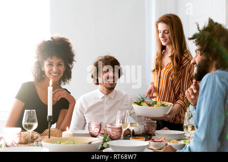Friends having fun at a dinner party, enjoying eating together Stock Photo