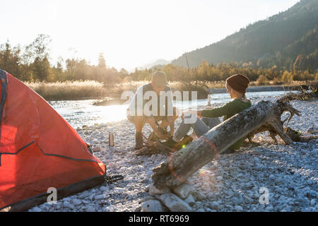 Mature couple camping at riverside, collecting wood for a camp fire Stock Photo