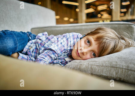 Portrait of boy lying on couch with earphones Stock Photo