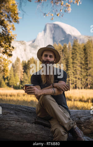 USA, California, portrait of bearded man sitting on a log in Yosemite National Park Stock Photo