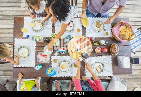 Flat-lay of friends eating  together. Top view of people having party, gathering, celebrating at wooden rustic table set with various  snacks and fing Stock Photo
