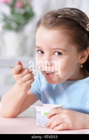 Portrait of cute little girl eating delicious yogurt Stock Photo