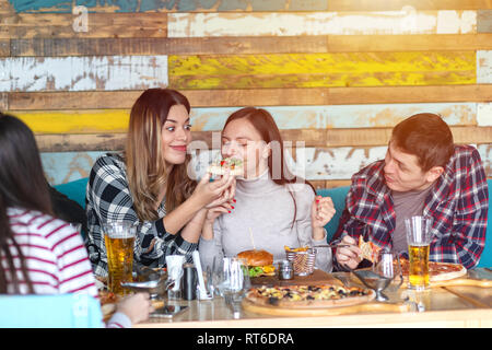 Group of happy friends having lunch sharing pizza in modern pub Stock Photo