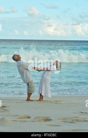 Portrait of happy elderly couple dancing on tropical beach Stock Photo