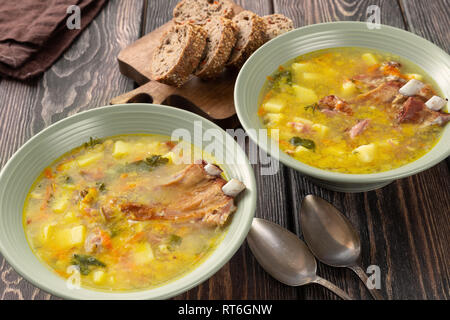 Two plates of delicious yellow split peas soup with smoked pork ribs  on a wooden table. Stock Photo