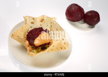Vegetarian burger in corn tortillas with beetroot, carrots, onions, cabbage and green salad, chickpeas and avocados on a plate, on a white background Stock Photo