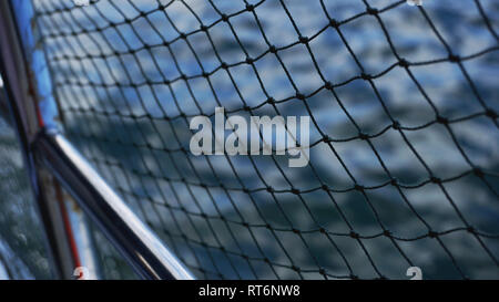 Safety net on boat. Ropes on boat. Safety ropes and blue sea. Waves on the sea and safety mesh. Stock Photo