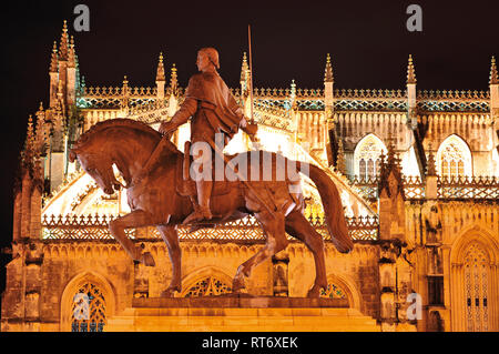 Nocturnal and lateral view of gothic monastery and pedestrian statue of medieval knight Stock Photo