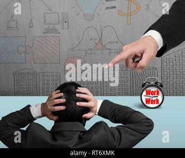 Hand pointing at another businessman holding head, with alarm clock on table and business concepts doodles wall background. Stock Photo