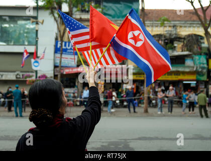 Hanoi, Vietnam. 28th Feb, 2019. February 28, 2019 - Hanoi, Vietnam - A local Vietnamese woman holds up the national flags of the United States, Vietnam and North Korea as she waits for Kim Jong Un's motorcade to drive back to his hotel during the second North Korea-U.S. Summit in the capital city of Hanoi, Vietnam. The meeting between U.S. President Donald Trump and North Korean Leader Kim Jong Un was cut short today as no agreement could be made between the two leaders at this point. Credit: Christopher Jue/ZUMA Wire/Alamy Live News Stock Photo